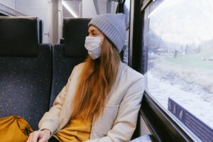 female sitting on train wearing face mask